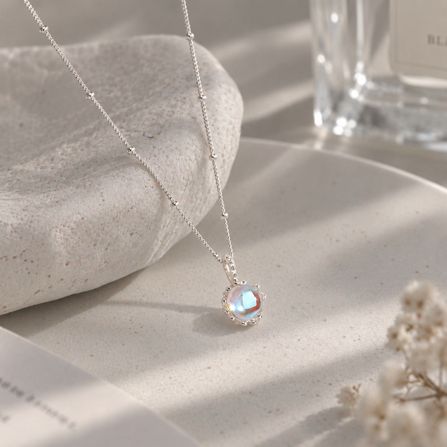 Sparkling Aurora Moonstone Pendant Satellite Necklace on stone display
